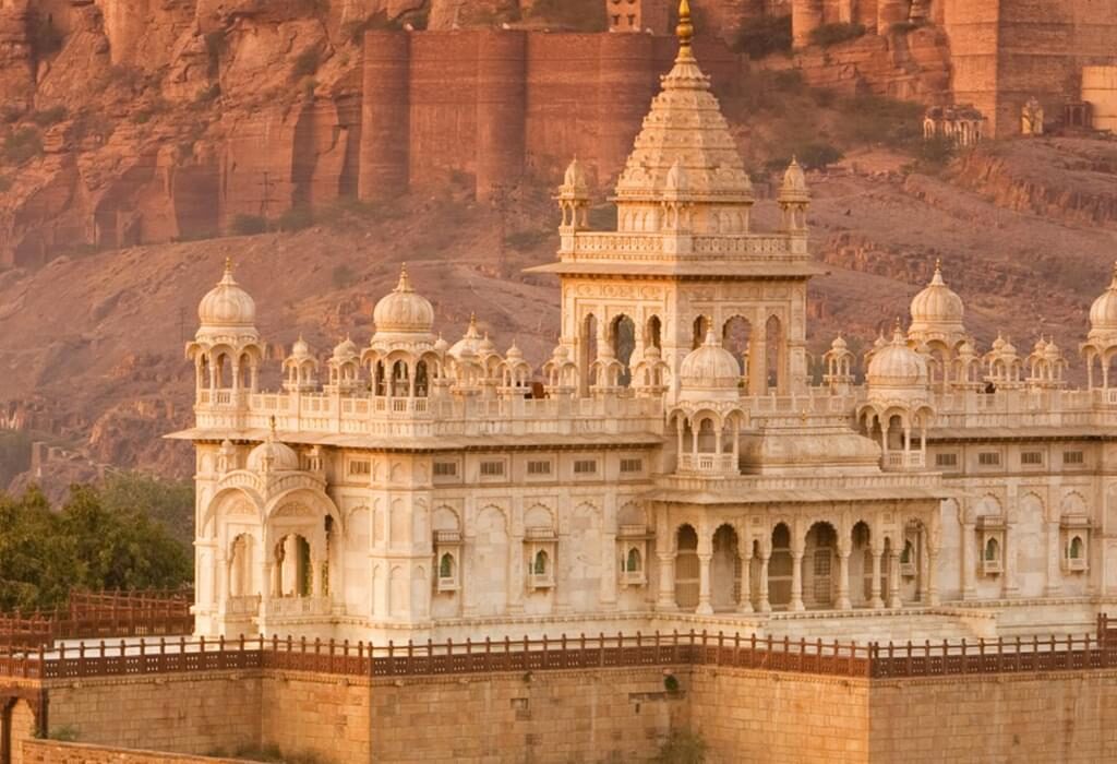 "View of Jaswant Thada in Jodhpur, India, with the imposing Mehrangarh Fort in the background at sunset."