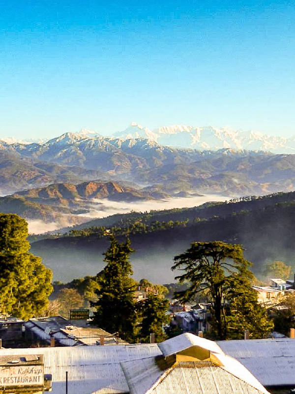 "A serene view of Nainital, with its emerald-green lake surrounded by lush hills and colorful boats floating on the water."