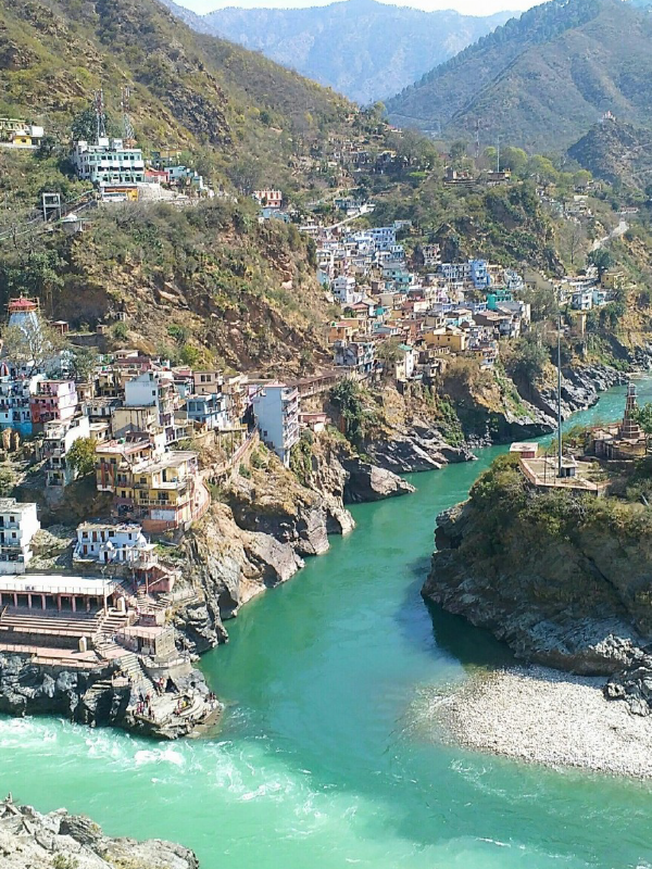 "A serene view of Nainital, with its emerald-green lake surrounded by lush hills and colorful boats floating on the water."